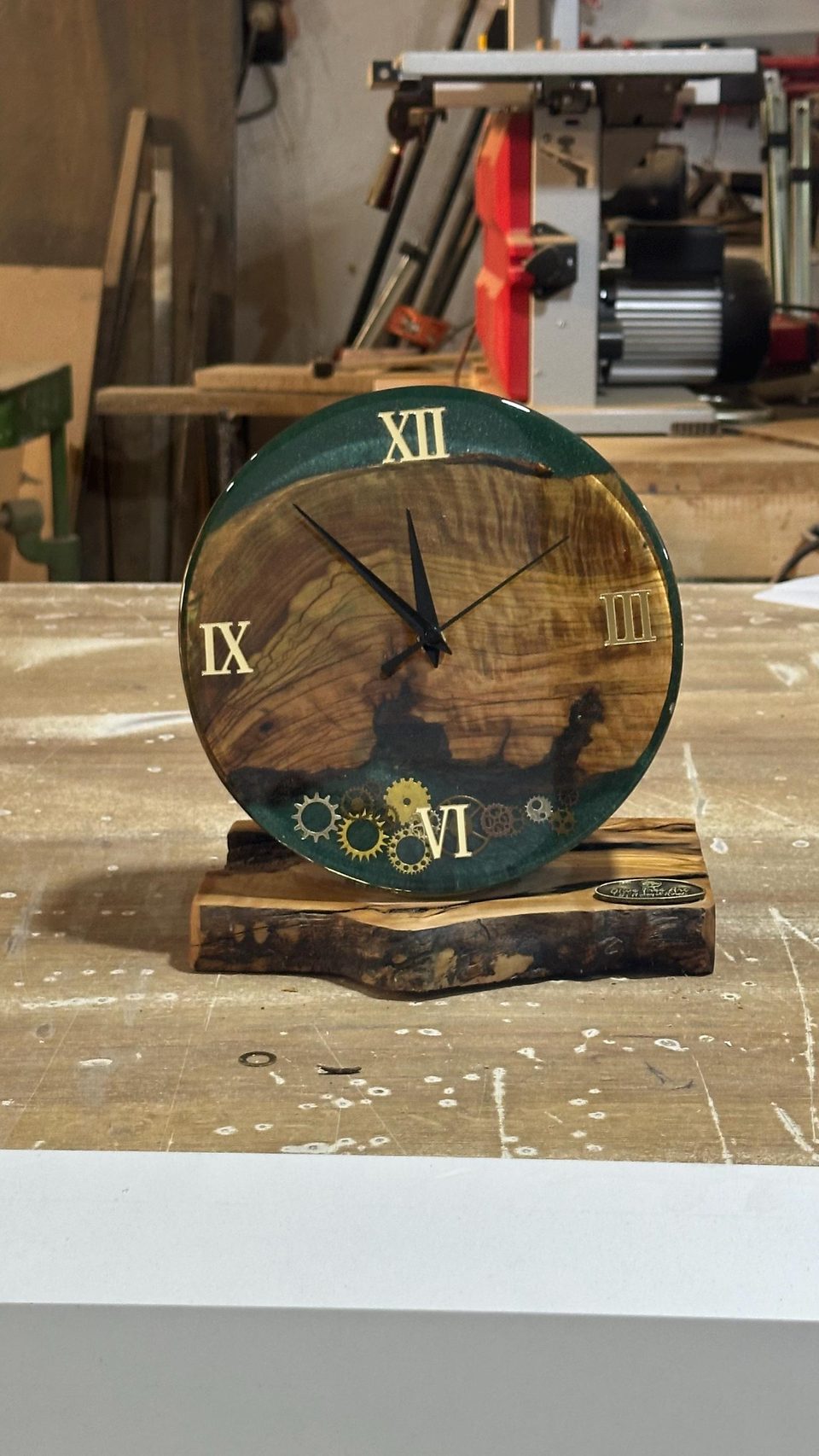 The clock on its live-edge wood base on a workbench in the workshop