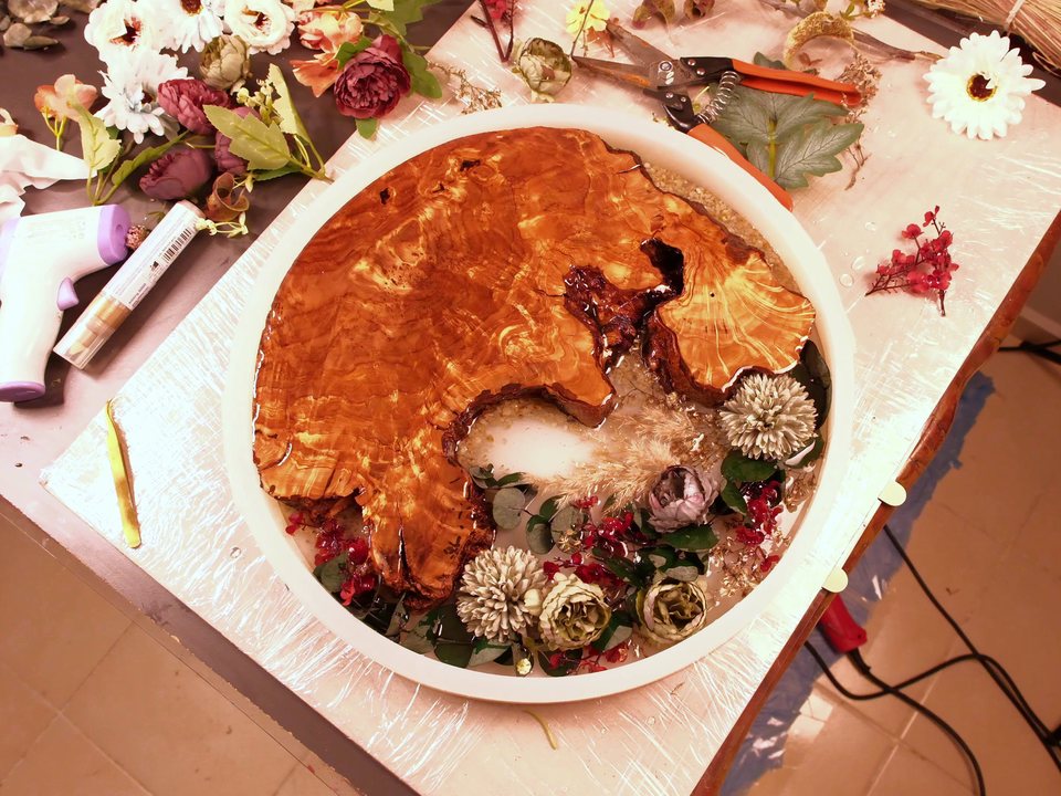 The workshop table: a round mold with olive wood and flowers, scissors and dried blooms around it
